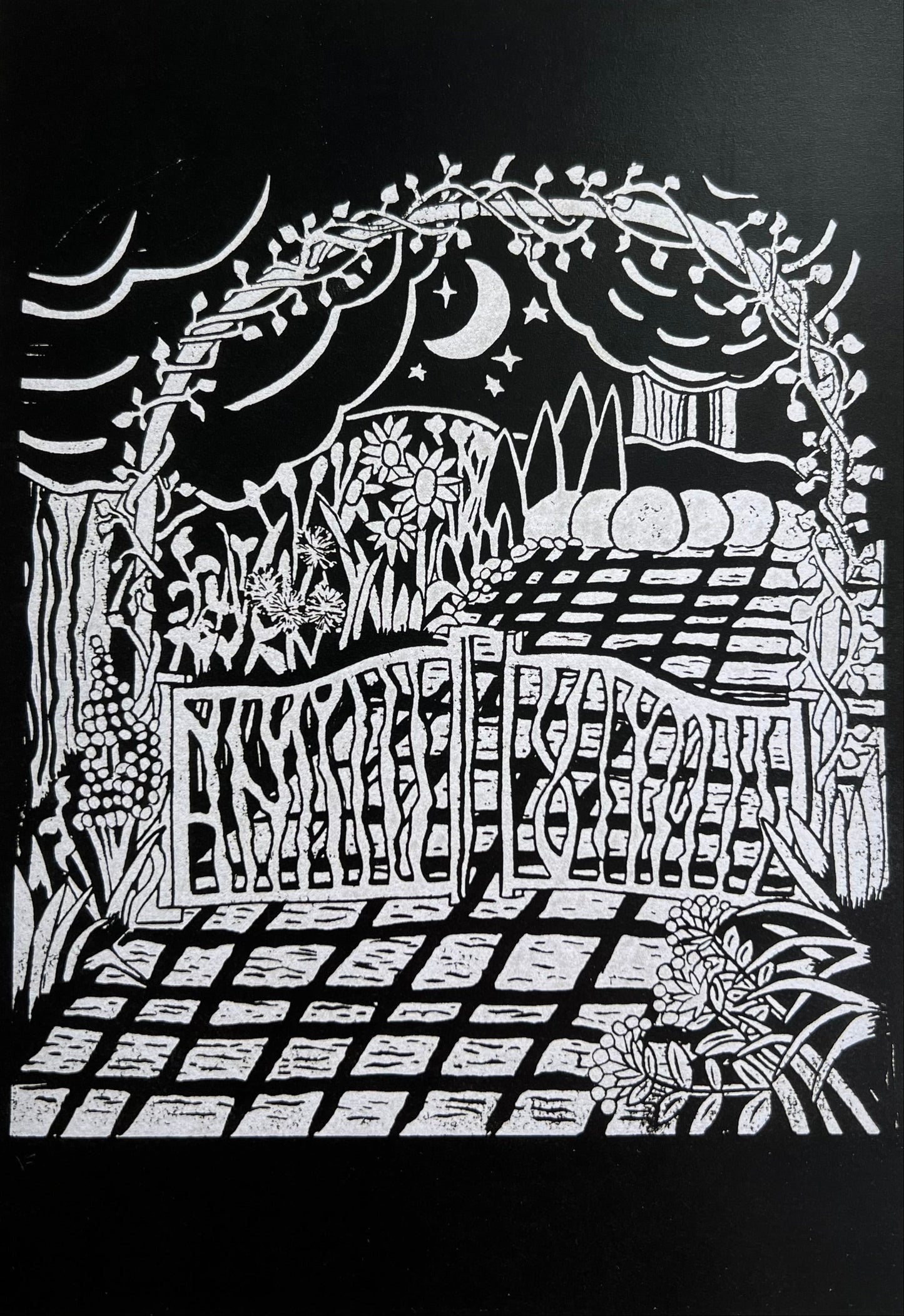 A greetings card featuring a black and silver linocut print of a garden pathway and trees with a moon and stars overhead.